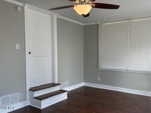 empty room with baseboards, visible vents, wood finished floors, ceiling fan, and ornamental molding