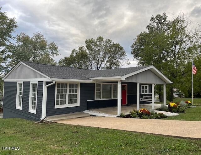 rear view of property featuring a lawn and a porch