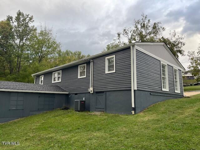 view of side of property with a lawn and cooling unit