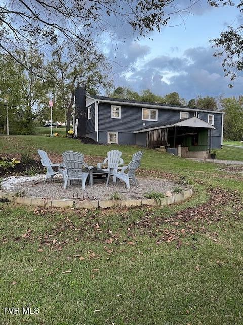 rear view of property featuring a lawn and an outdoor fire pit