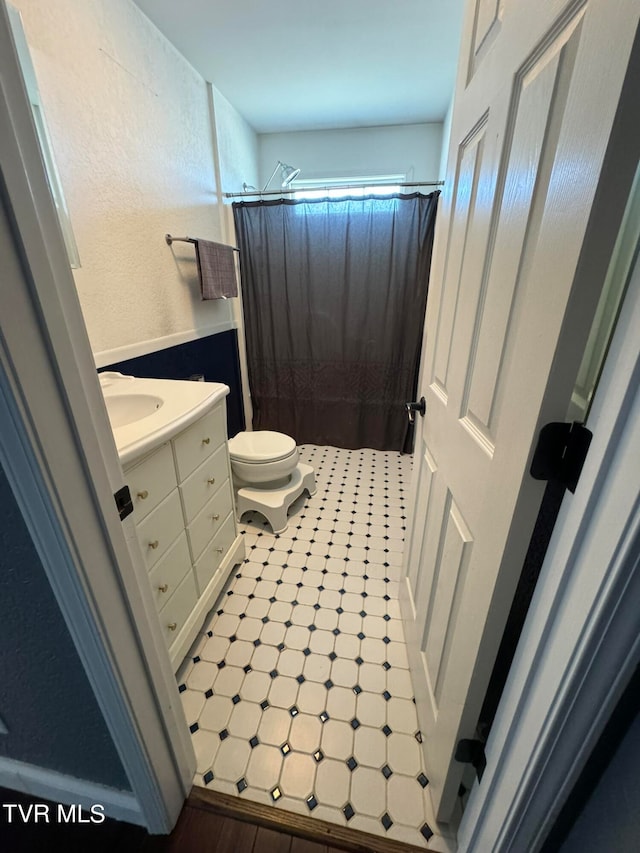 bathroom with tile patterned flooring, toilet, vanity, and curtained shower