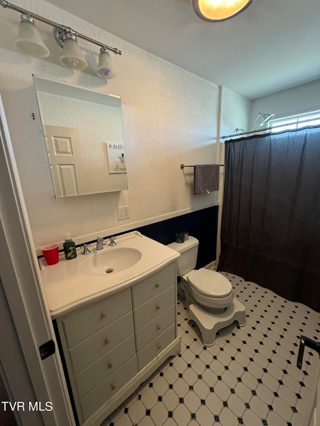 bathroom featuring tile patterned flooring, a shower with shower curtain, vanity, and toilet