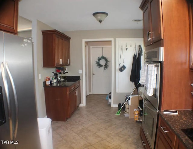 kitchen featuring light tile patterned floors, stainless steel refrigerator, black electric stovetop, and dark stone countertops