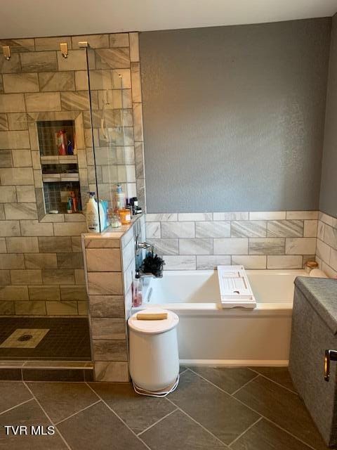 bathroom with separate shower and tub and tile patterned flooring