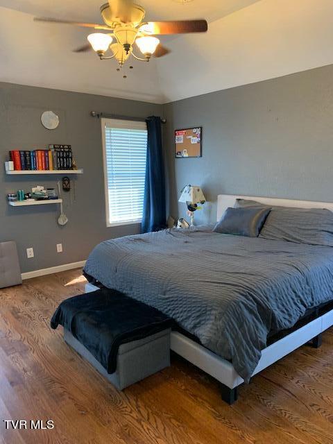 bedroom with ceiling fan, hardwood / wood-style floors, and vaulted ceiling