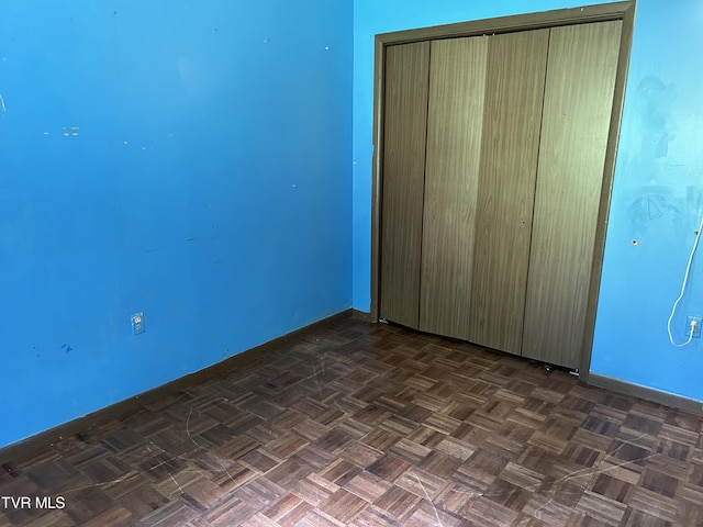 unfurnished bedroom with dark parquet floors and a closet