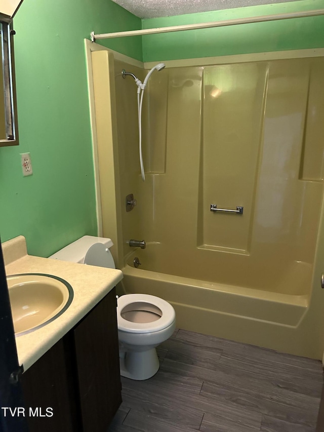 full bathroom featuring hardwood / wood-style floors, shower / bathing tub combination, vanity, a textured ceiling, and toilet