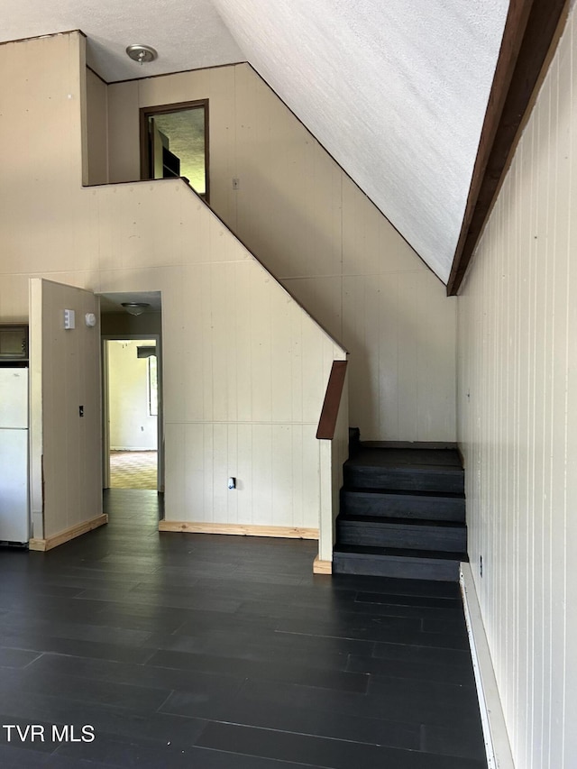 stairway with vaulted ceiling, hardwood / wood-style floors, and wood walls