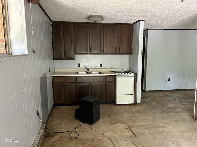 kitchen featuring sink, wood walls, and white range with electric cooktop