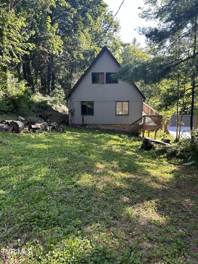 view of side of home with a wooden deck and a yard