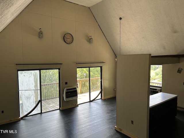 unfurnished living room with dark wood-type flooring, lofted ceiling, heating unit, and plenty of natural light