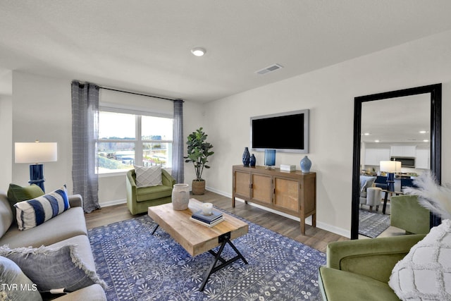 living area featuring visible vents, baseboards, and wood finished floors