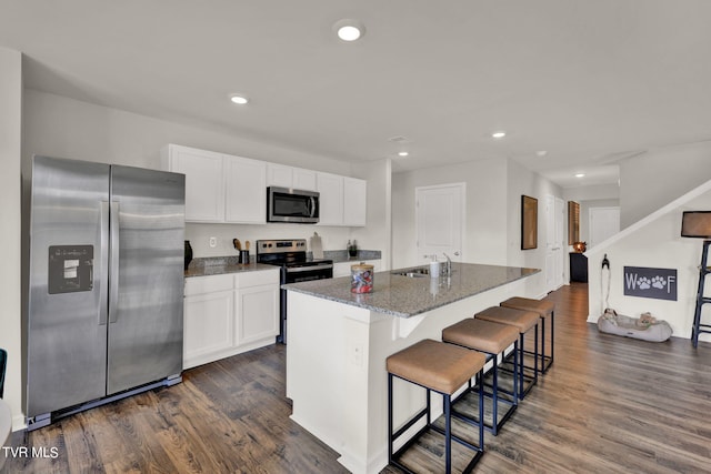 kitchen with appliances with stainless steel finishes, white cabinets, a center island with sink, and sink