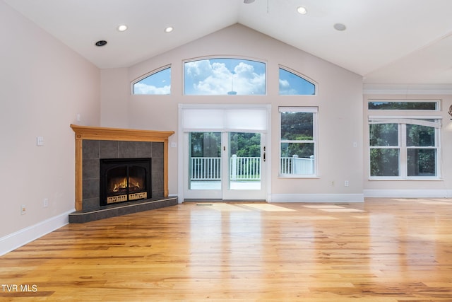 unfurnished living room with lofted ceiling, a fireplace, and light hardwood / wood-style flooring