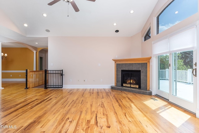 unfurnished living room with a fireplace, ceiling fan with notable chandelier, and light hardwood / wood-style flooring