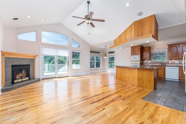 kitchen with tasteful backsplash, white appliances, hanging light fixtures, and light wood-type flooring