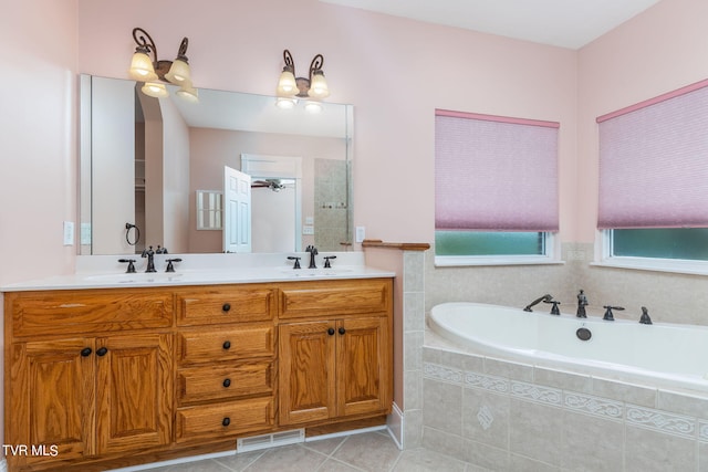 bathroom with tiled tub, vanity, and tile patterned floors