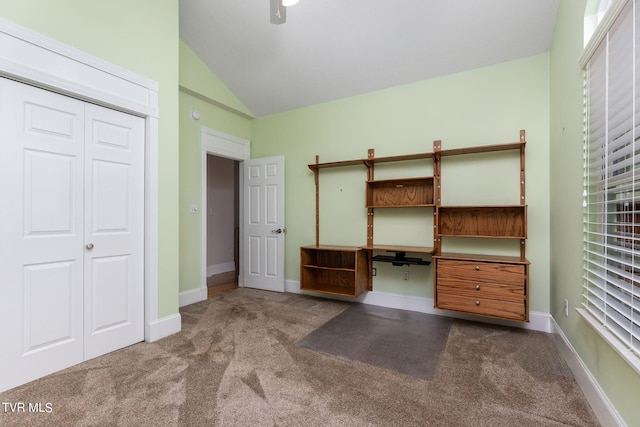 unfurnished bedroom with built in desk, high vaulted ceiling, carpet flooring, a closet, and ceiling fan