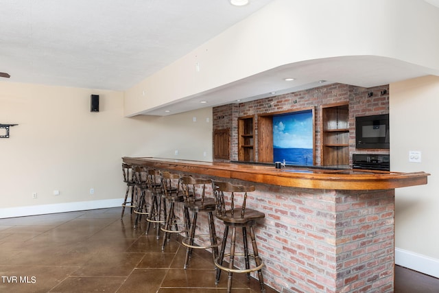 bar featuring black microwave, dark tile patterned floors, and range