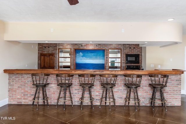 bar with wall oven, dark tile patterned flooring, and black microwave