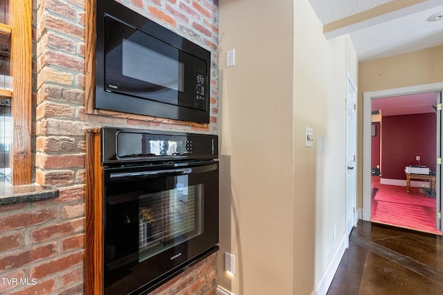 kitchen featuring brick wall and black appliances