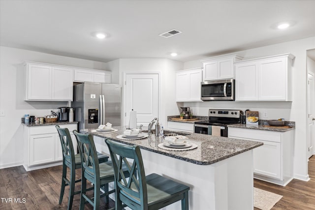 kitchen with dark hardwood / wood-style floors, sink, an island with sink, stainless steel appliances, and white cabinets