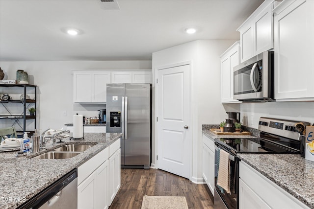 kitchen featuring light stone counters, white cabinets, appliances with stainless steel finishes, and sink