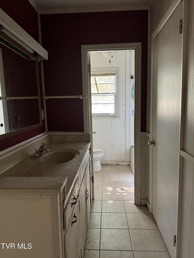 bathroom with tile walls, a bathtub, vanity, toilet, and tile patterned floors