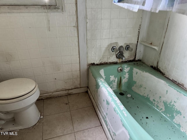 bathroom featuring tile walls, tile patterned floors, a tub, and toilet