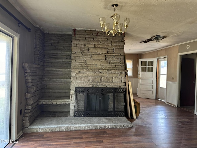 unfurnished living room featuring crown molding, an inviting chandelier, hardwood / wood-style floors, a fireplace, and a textured ceiling