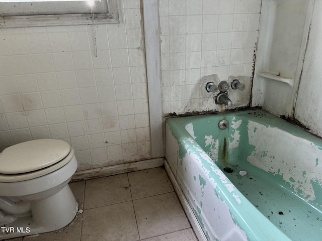 bathroom with tile patterned flooring, a bathtub, and toilet