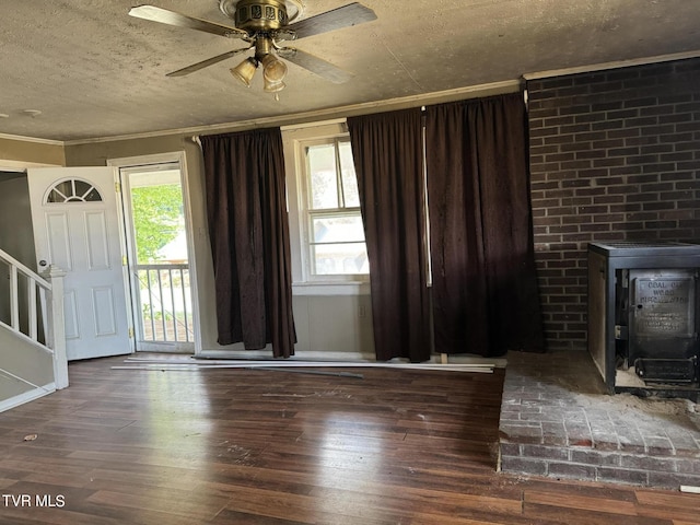 entryway featuring ornamental molding, dark hardwood / wood-style floors, ceiling fan, and a wood stove