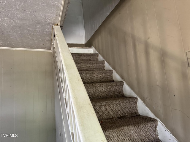 staircase featuring wood walls