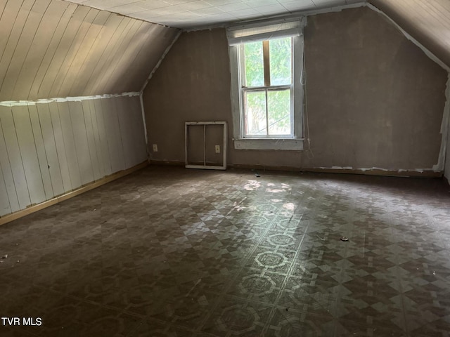 bonus room with lofted ceiling and wood walls