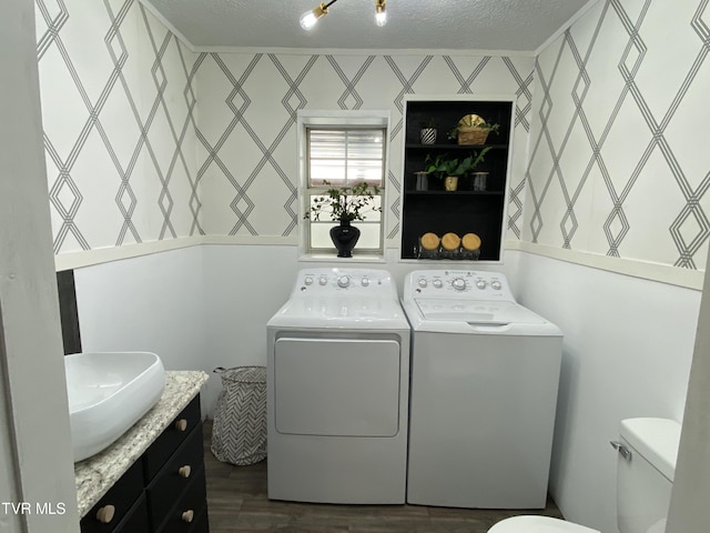 laundry room featuring sink, a textured ceiling, dark hardwood / wood-style floors, and washing machine and clothes dryer