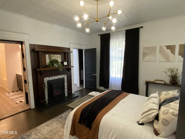 bedroom with a brick fireplace, ensuite bathroom, dark hardwood / wood-style flooring, and a notable chandelier