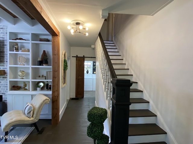 stairway featuring a barn door, washing machine and dryer, a notable chandelier, and built in features