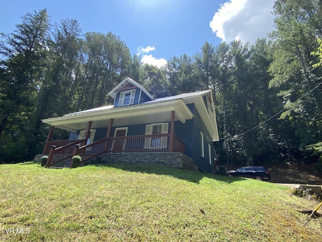 view of front of property featuring a front lawn, central AC unit, and covered porch