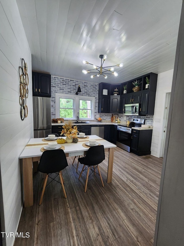 kitchen with decorative backsplash, appliances with stainless steel finishes, brick wall, and wood-type flooring