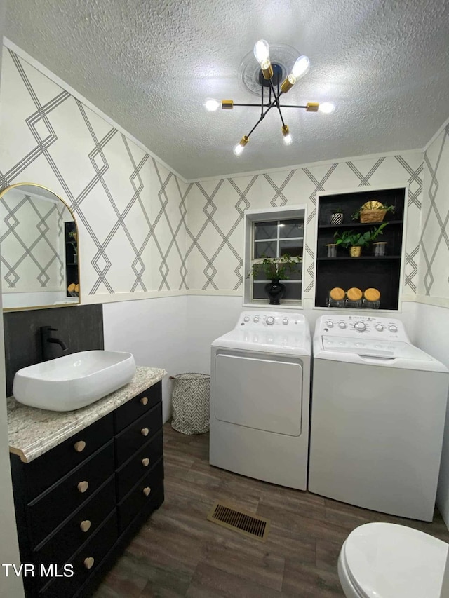 bathroom featuring toilet, an inviting chandelier, separate washer and dryer, wood-type flooring, and a textured ceiling