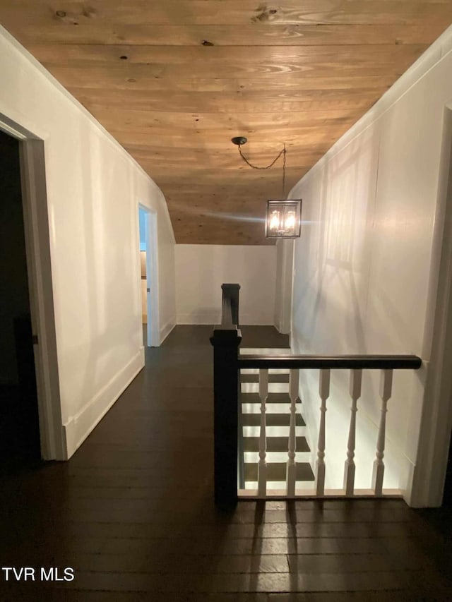 hallway with wood ceiling, dark hardwood / wood-style flooring, and an inviting chandelier