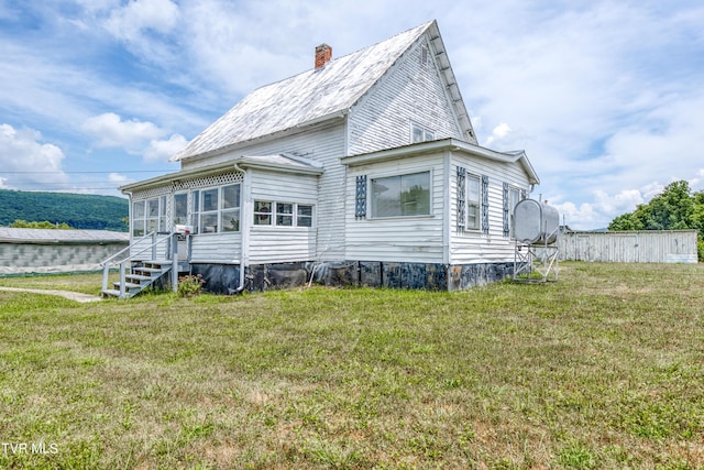 rear view of property with a yard and a sunroom