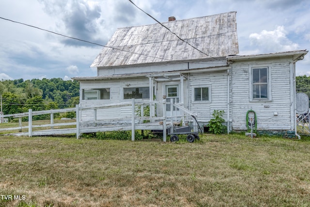 back of property featuring a deck and a lawn