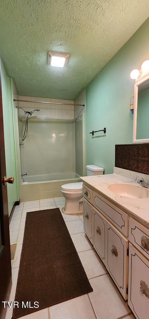 full bathroom with shower / bathtub combination, tile patterned flooring, vanity, toilet, and a textured ceiling