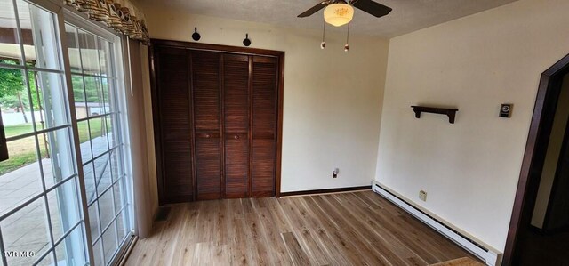 unfurnished bedroom featuring light wood-type flooring, a baseboard radiator, a closet, ceiling fan, and access to exterior