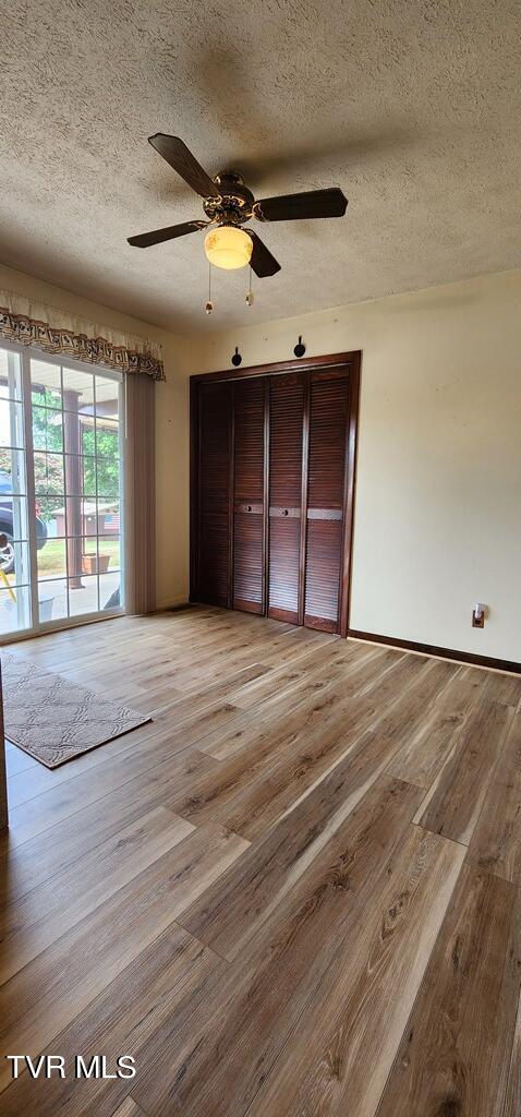 unfurnished bedroom with ceiling fan, access to outside, a textured ceiling, and light wood-type flooring