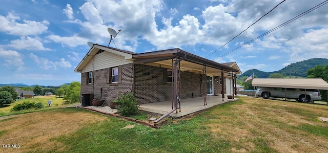 view of side of home with a carport, a mountain view, a yard, and central AC unit