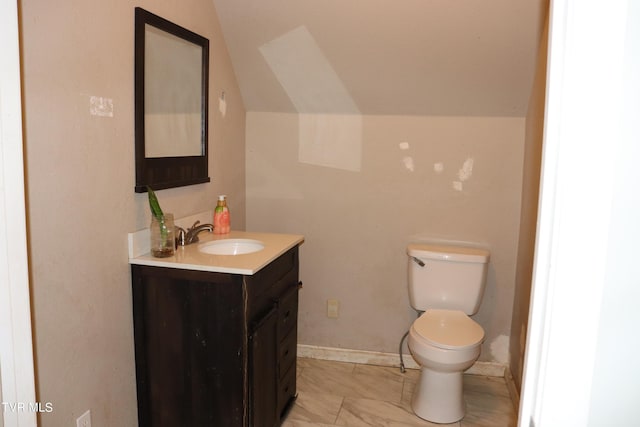 bathroom with lofted ceiling, toilet, and vanity