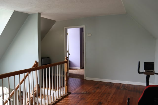 additional living space with dark wood-type flooring, vaulted ceiling, and a textured ceiling