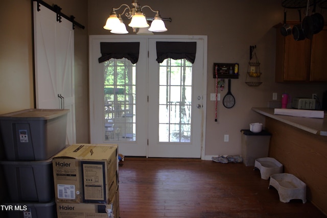 doorway to outside featuring dark hardwood / wood-style flooring, a barn door, and an inviting chandelier